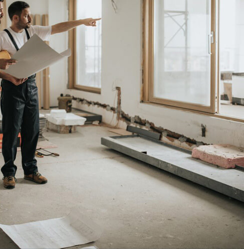 Entrepreneurs en rénovation examinant des plans sur un chantier intérieur